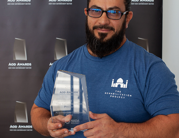 Bearded man with glasses holding award